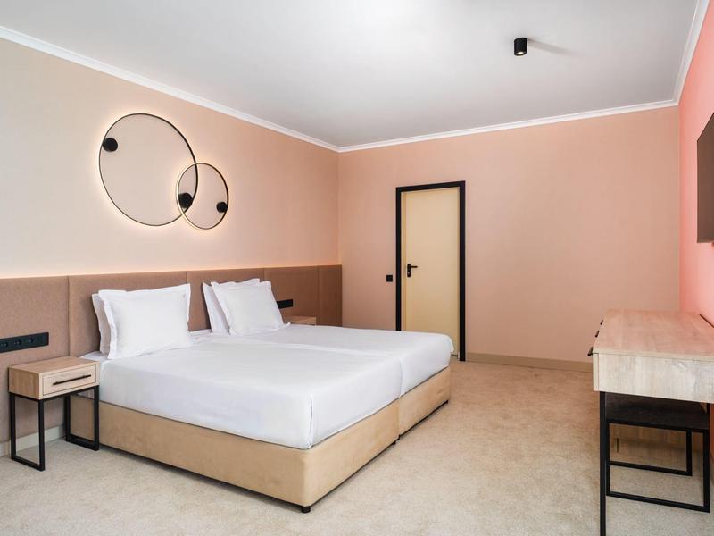 Camera d'hotel moderna con letto grande, arte da parete e arredamento semplice in toni caldi.