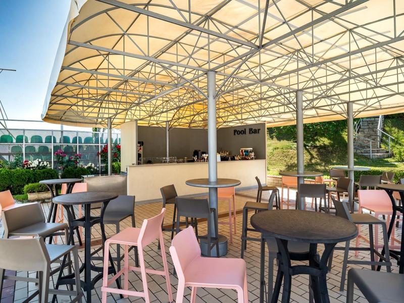 Area esterna coperta con tavoli e sedie accanto alla natura verde