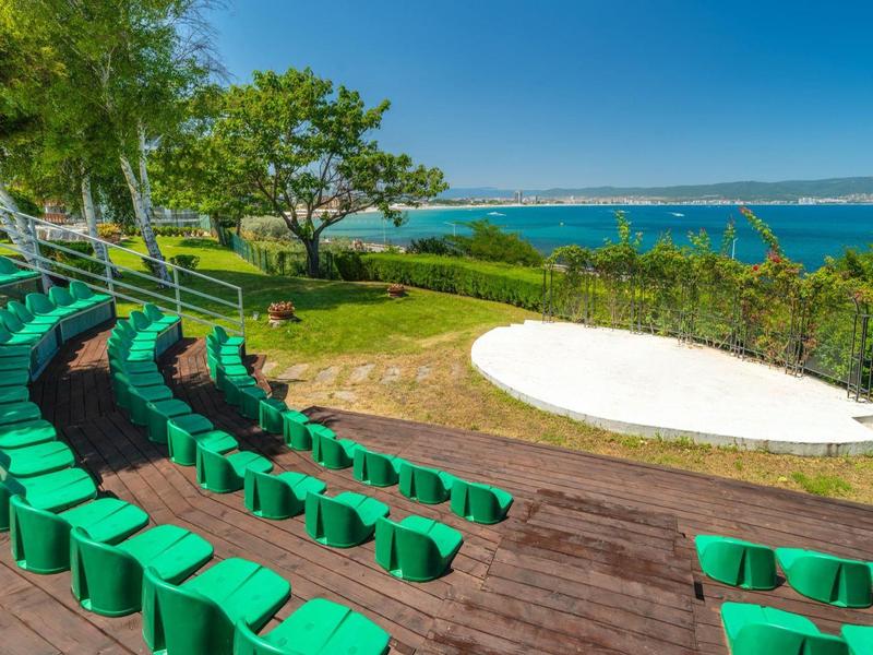 Anfiteatro verde con vista sul mare blu sotto un cielo sereno.