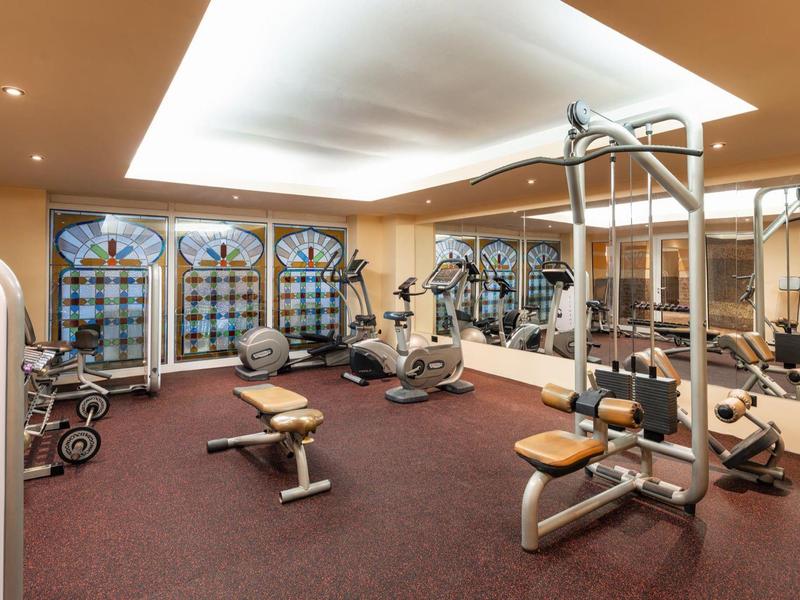 Palestra luminosa con varie attrezzature da allenamento e grandi specchi alle pareti