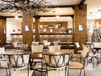 Eleganter Hotelbarbereich mit Holzvertäfelungen und weißen gepolsterten Stühlen.