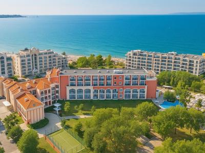 Blick auf Hotelgebäude mit Poolanlage am Meer in sonniger Umgebung.