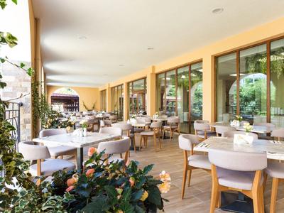 Überdachte Außenterrasse eines Restaurants mit gedeckten Tischen und Holzmöbeln.
