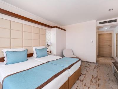 Modernes Hotelzimmer mit zwei Einzelbetten, blauen Akzenten und gemütlichem Sitzbereich.