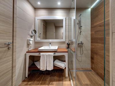 Modernes Badezimmer mit Holzvertäfelung, Waschbecken, Spiegel und abgetrennter Dusche.