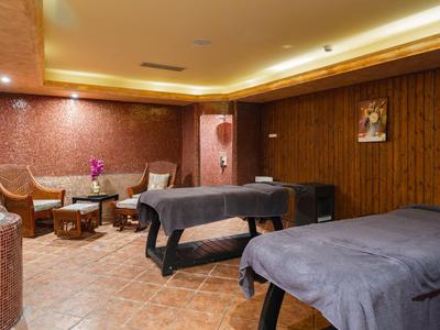 Ein entspannender Spa-Raum mit zwei Massageliegen, Holzwänden und gedämpftem Licht.