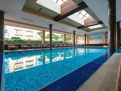 Innenpool mit blauem Wasser und Liegestühlen in einem modernen Hotel.