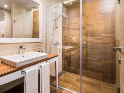 Modernes Badezimmer mit Holzfliesen, Glasdusche und Waschbecken auf Holztisch.