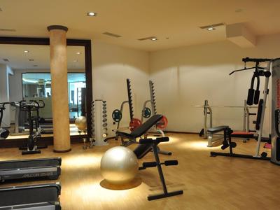 Innenansicht eines modernen Fitnessraums mit Trainingsgeräten und Hantelbank.