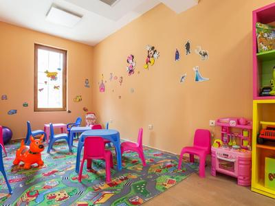 Buntes Kinderspielzimmer mit kleinen Tischen, Stühlen und Spielzeug in einem Hotel.