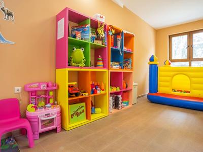 Bunter Kinderspielbereich mit Spielküche, Aufbewahrungswürfeln und Hüpfburg vor Fenster.