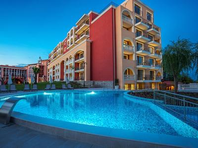 Moderner Hotelkomplex mit beleuchtetem Außenpool bei Dämmerung.