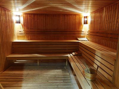 Saunaraum mit Holzverkleidung, Holzbänken und warmem Licht für Entspannung.
