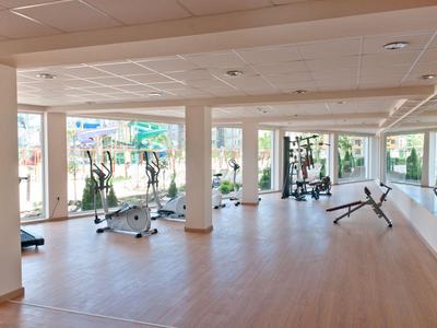 Velká posilovna s různými cvičebními stroji a velkými okny s výhledem ven