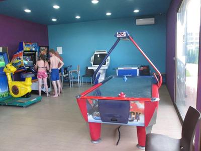 Binnen arcade ruimte met airhockeytafel, arcadespellen en spelende kinderen erbij.