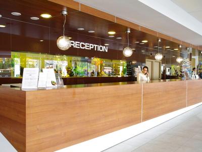 Moderní hotelová recepce s dlouhým dřevěným pultem a dobře osvětlenou oblastí.