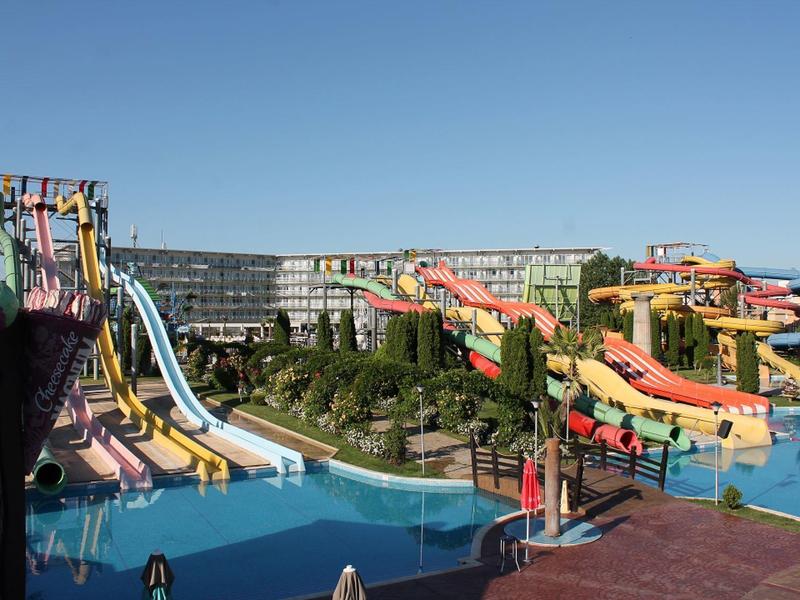 Groot waterpark met meerdere kleurrijke glijbanen en hotelgebouwen op de achtergrond.
