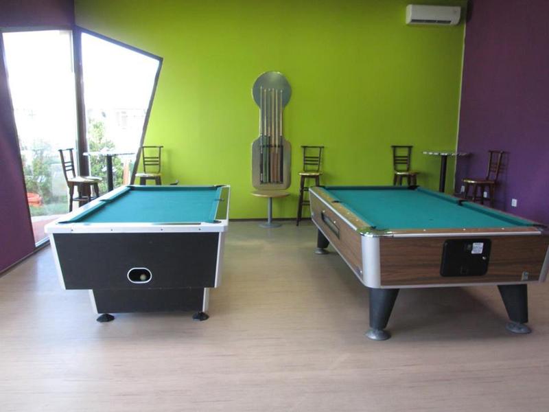 Interieurkamer met twee pooltafels en felle groene en paarse muren.