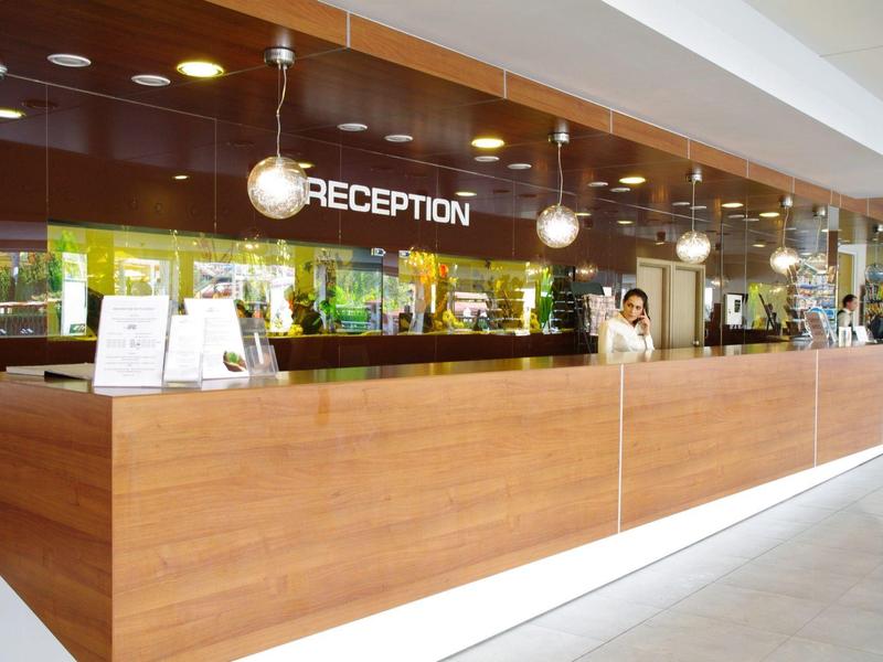 Moderne hotelreceptie met houten voorkant en verlichte signage.