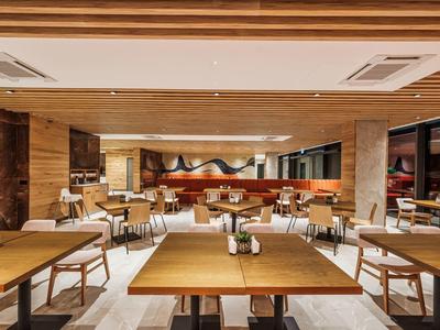 Salle de restaurant d'hôtel moderne avec tables en bois et chaises confortables.