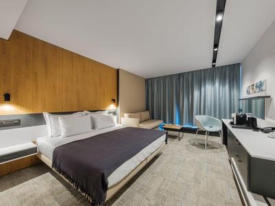 Chambre d'hôtel moderne avec lit double, mur en bois, coin salon et bureau