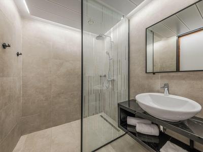 Salle de bains moderne avec douche à l'italienne, vasque sur plan et grand miroir.