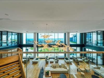 Grand salon d'hôtel moderne avec fenêtres panoramiques et espaces assis élégants.