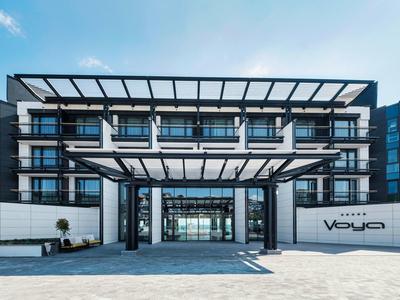 Bâtiment d'hôtel moderne avec façade en verre et entrée couverte sous un ciel clair.