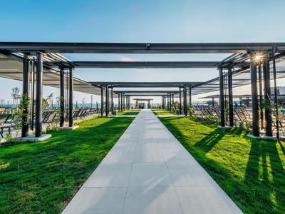 Allée droite avec auvents ombragés à côté d'une pelouse verte sous un ciel clair.