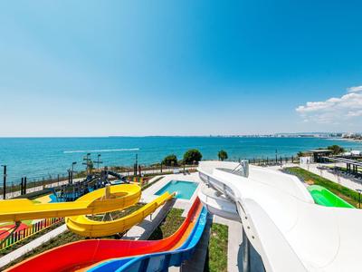 Toboggans aquatiques colorés avec vue sur la mer dans un parc d'attractions côtier.