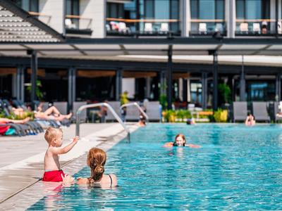 Des enfants jouent avec des pistolets à eau à la piscine de l'hôtel par une journée ensoleillée.