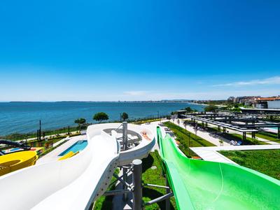 Toboganes de agua y mar claro bajo cielos soleados en un complejo vacacional.