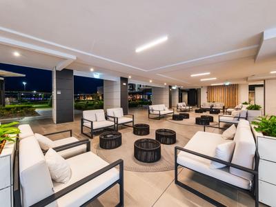 Área de lounge exterior moderna con grupos de asientos e iluminación nocturna.