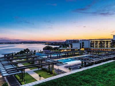 Complexe hôtelier moderne avec piscine et vue sur la mer au coucher du soleil