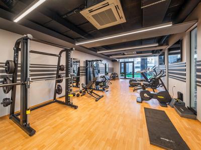 Gimnasio moderno con suelo de madera, equipos de ejercicio y grandes ventanas con vista.