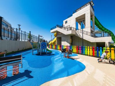 Parc aquatique extérieur avec toboggans et clôture colorée sous un ciel bleu clair.