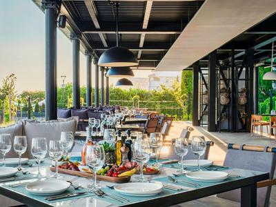 Terrasse élégamment dressée avec table à manger, verres et vue sur la verdure au coucher du soleil.