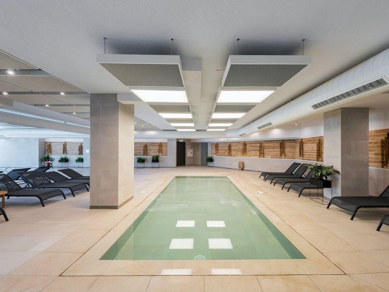 Espace piscine intérieure moderne avec chaises longues et panneaux en bois.