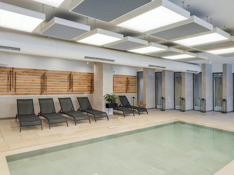 Piscine intérieure moderne avec chaises longues et éclairage indirect au plafond