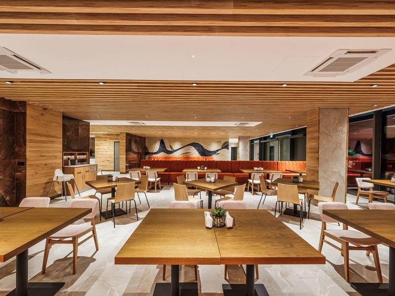 Salle de restaurant d'hôtel moderne avec tables en bois et chaises confortables.