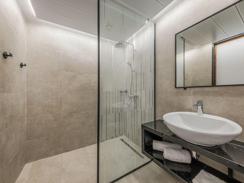 Salle de bains moderne avec douche à l'italienne, vasque sur plan et grand miroir.