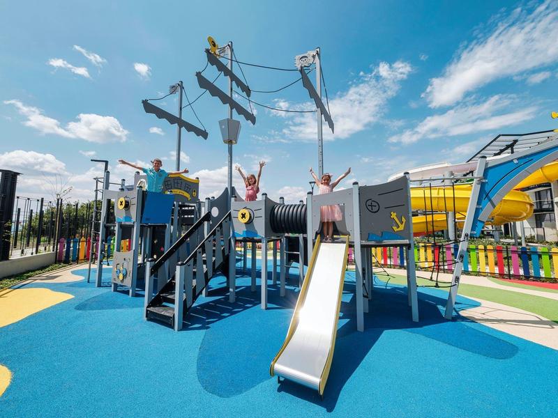 Aire de jeux colorée pour enfants avec toboggans et structures d'escalade sous un ciel bleu.
