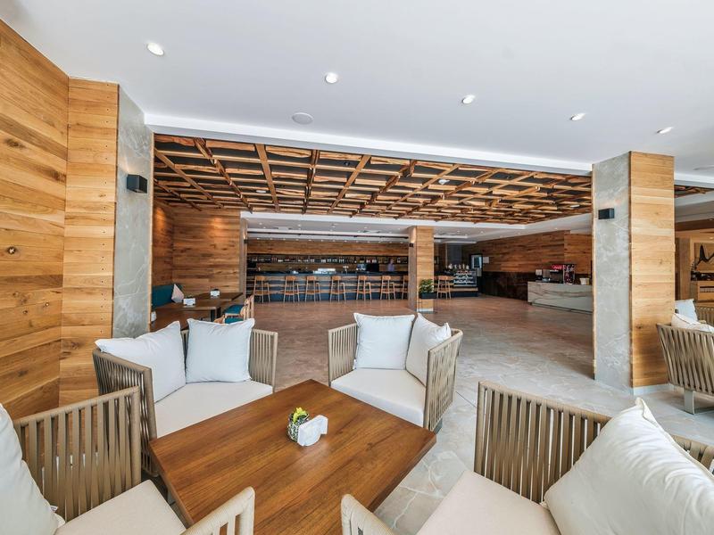 Salon d'hôtel lumineux et moderne avec accents en bois et coins sièges confortables.