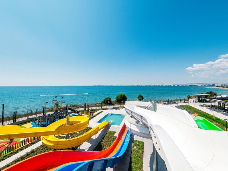 Toboggans aquatiques colorés avec vue sur la mer dans un parc d'attractions côtier.