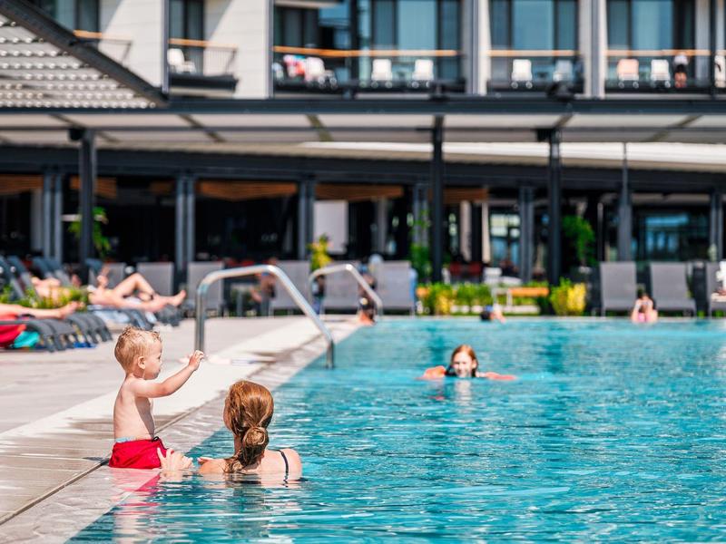 Des enfants jouent avec des pistolets à eau à la piscine de l'hôtel par une journée ensoleillée.
