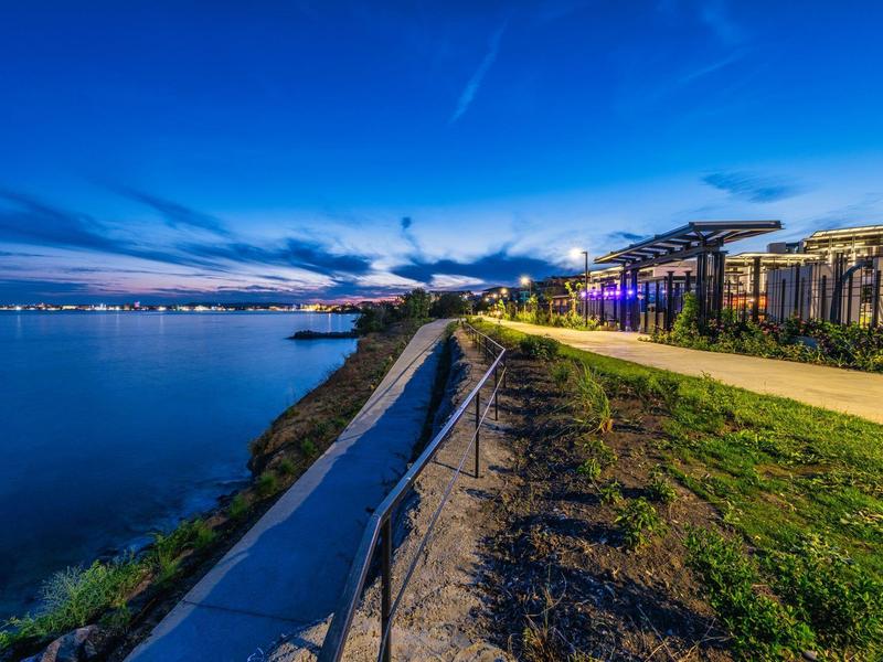 Sentier le long de l'eau au crépuscule avec promenade éclairée.