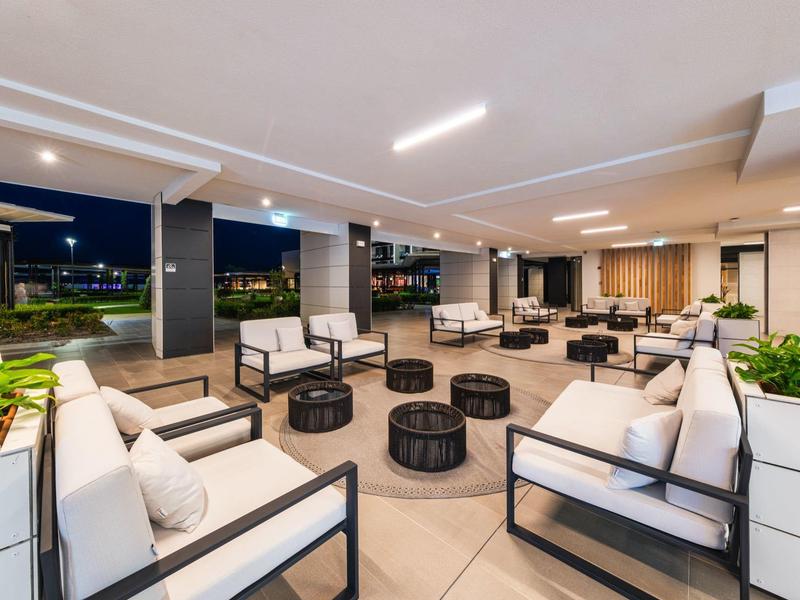 Salon d'hôtel moderne et ouvert avec fauteuils blancs et tables rondes la nuit.