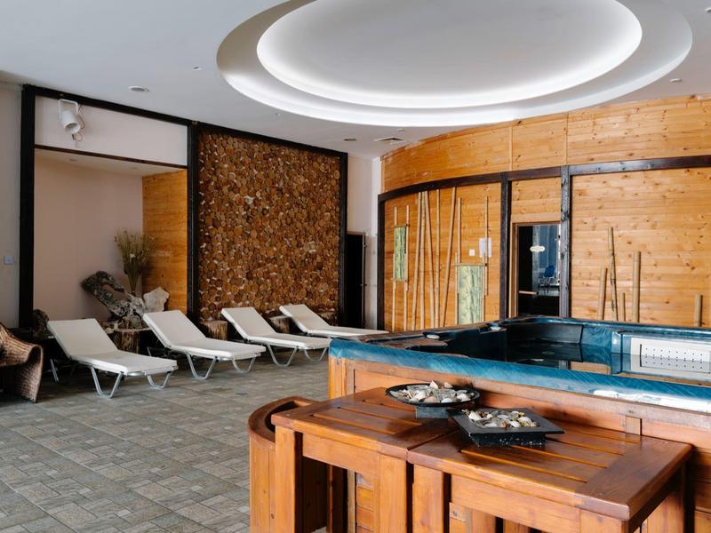 Moderne wellnessruimte met jacuzzi, ligstoelen en stijlvolle houten panelen.