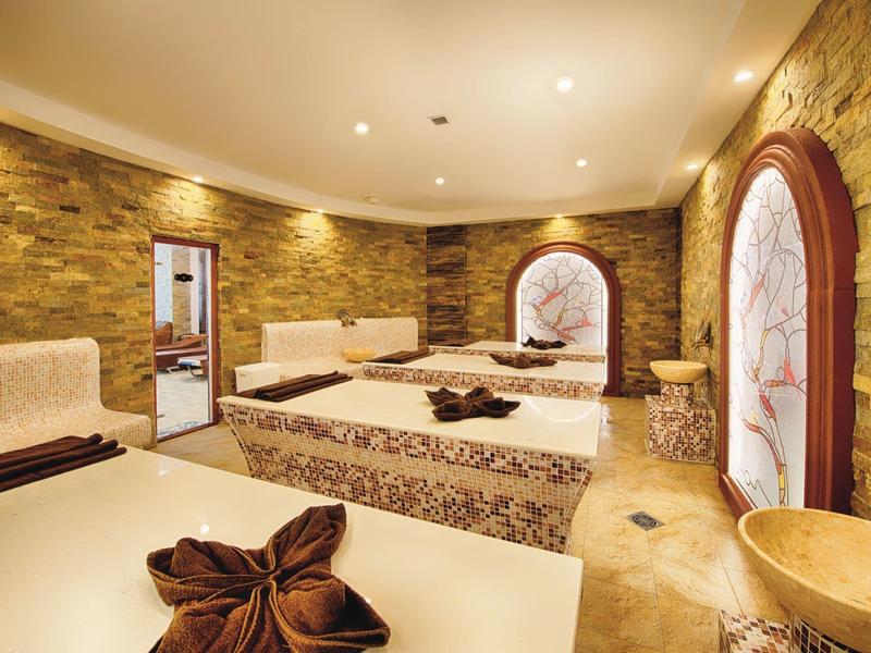 Elegante spa-ruimte met warm verlichte stenen muren en comfortabele ligbedden.