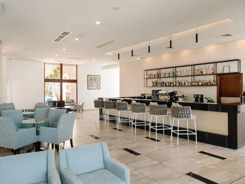 Lichte hotelbar met moderne inrichting, barkrukken en banken in een uitnodigende sfeer.